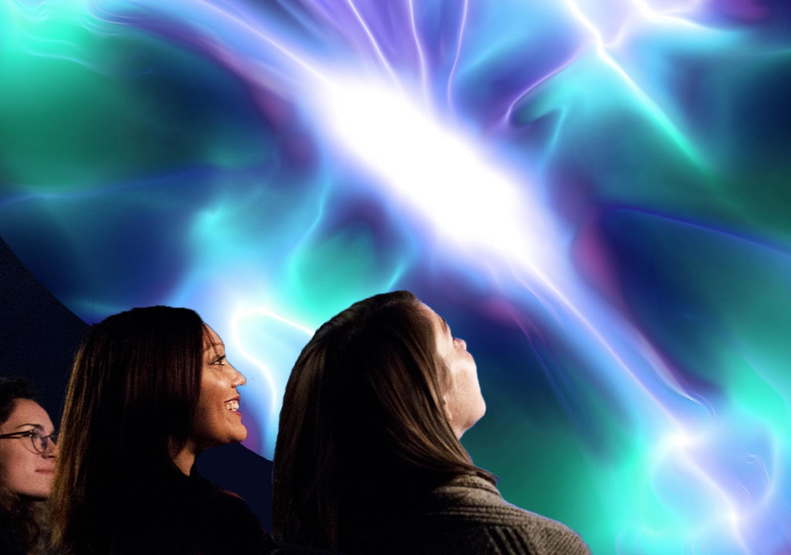 Close up of the profiles of 3 women as the look up at the planetarium dome which displays colorful lights and lasers.