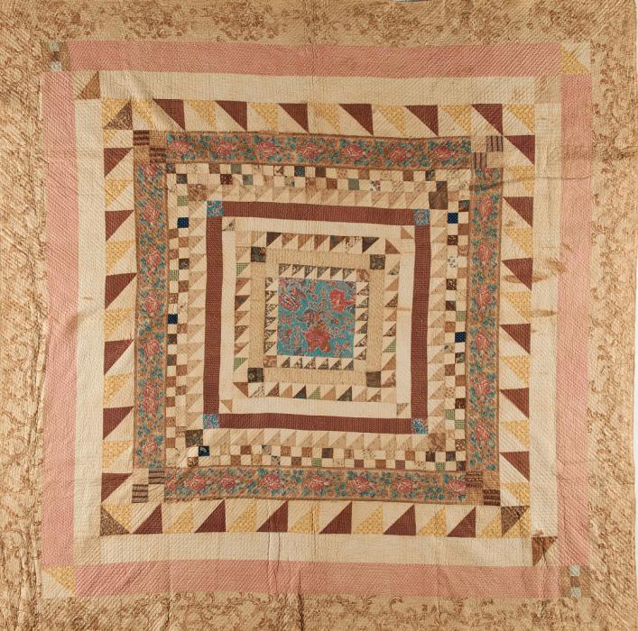 Quilt made of concentric squares in alternating patterns of triangles, checks, florals and solids. Colors are mostly pinks and shades of brown.