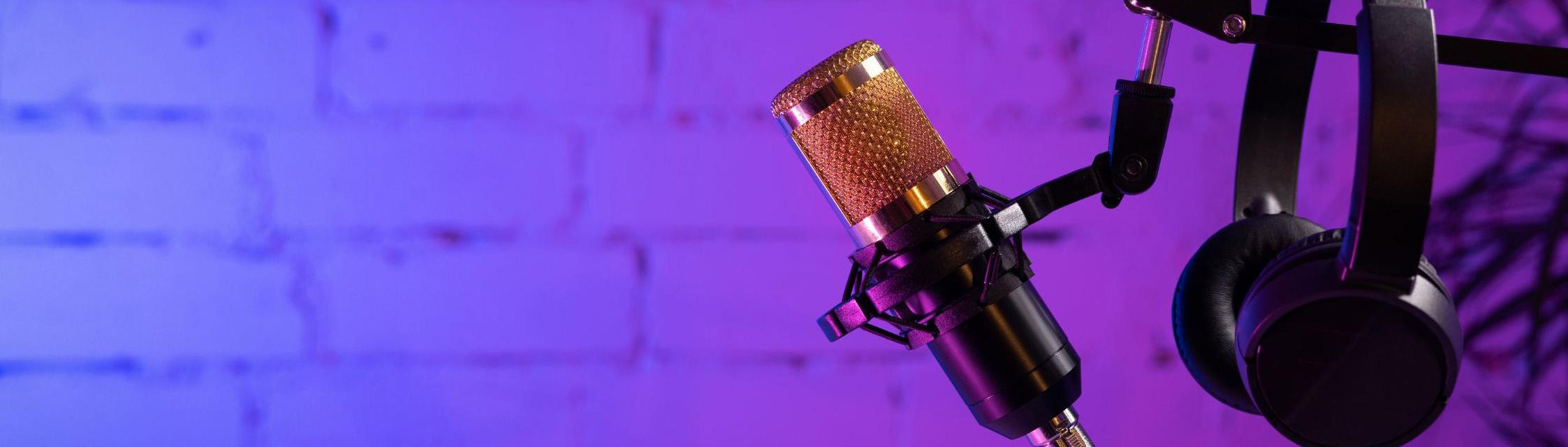 Headphones hang on a microphone stand with a purple and blue wall in the background