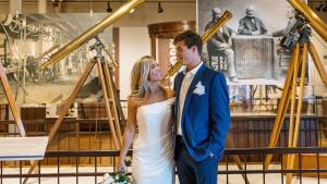 Bride and groom pose in front of telescopes on display at the South Carolina State Museum