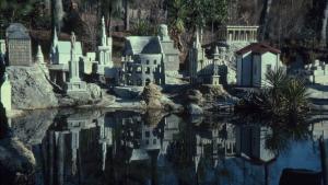 Collection of large building replicas of classical architecture made in concrete set up outdoors with a small pond in the foreground