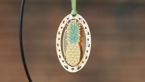 Oval Shaped Metal Ornament With Pineapple in the Center of the Oval