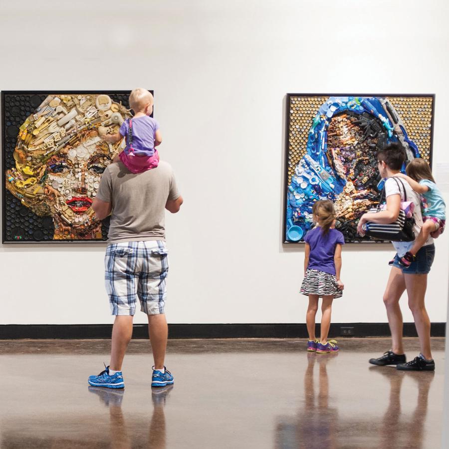 Family looks at 3 pieces of art displayed on a wall, including a portrait of Marilyn Monroe