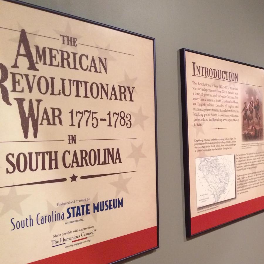 Tan wall with 7 text panels hanging on the wall about the American Revolutionary War in South Carolina