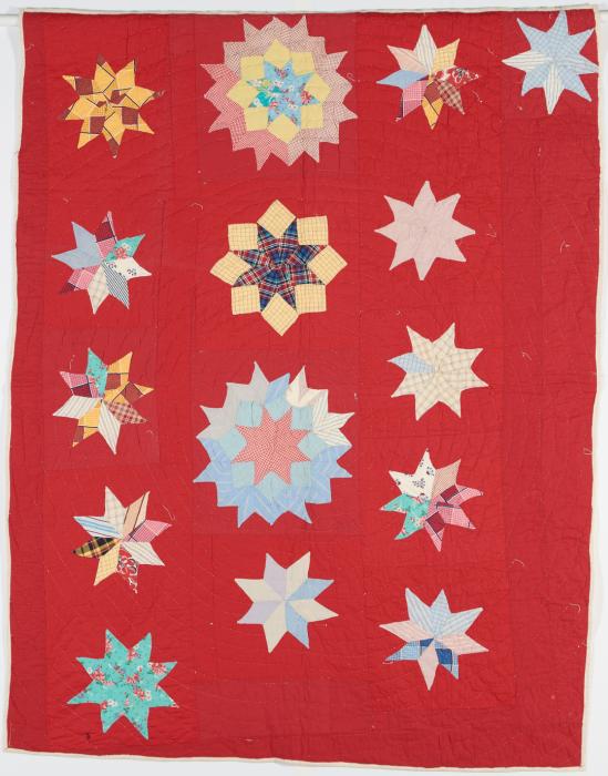 a quilt with multi colored stars on a field of red