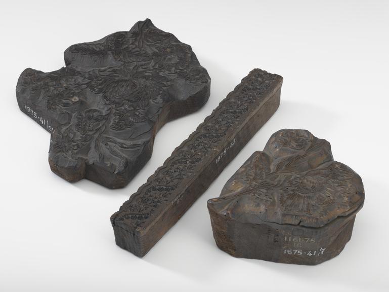 Three pieces of wood with carved designs on the side facing up